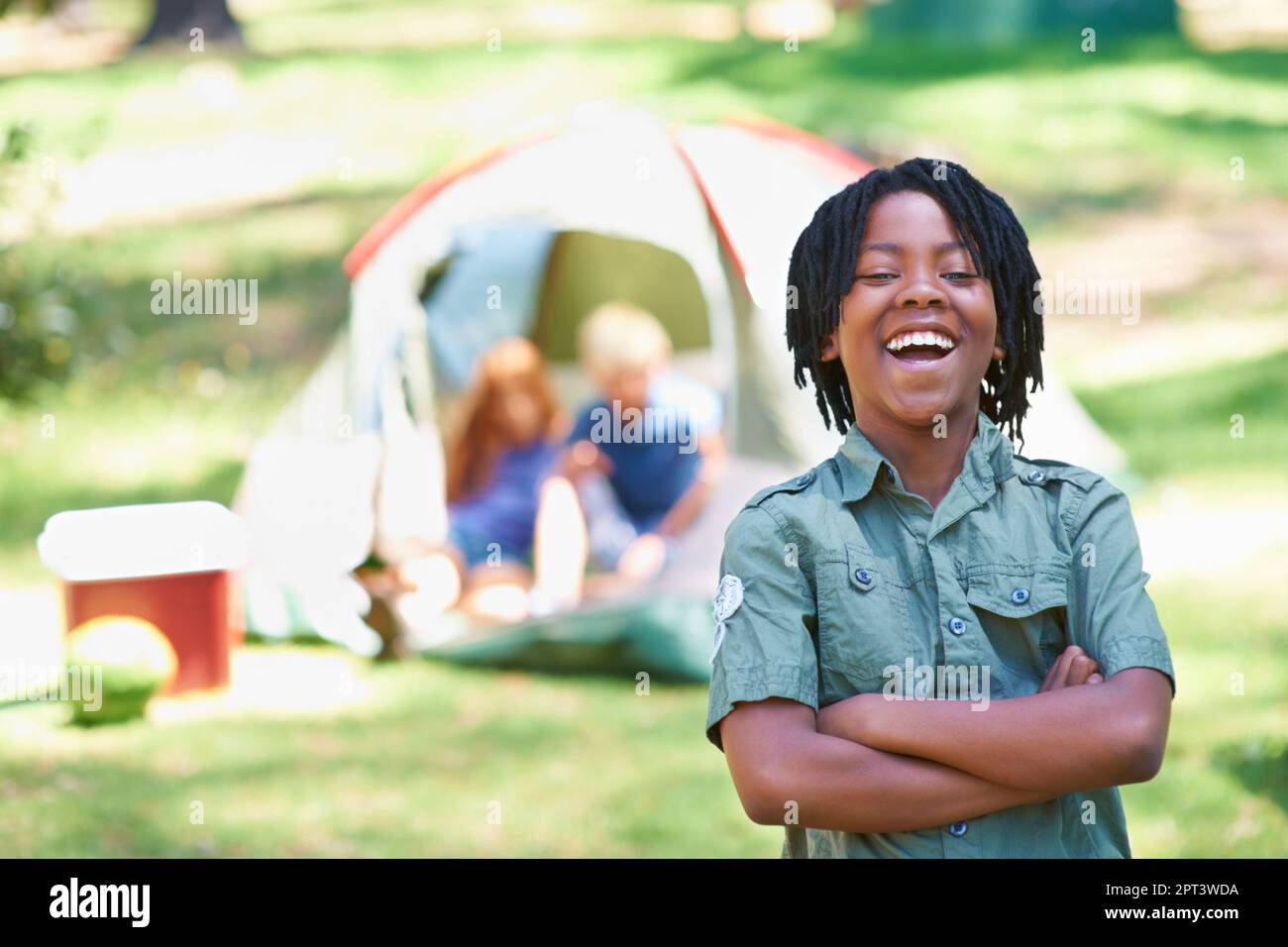 Braving The Great Outdoors A Boy Standing In Front Of His Campsite