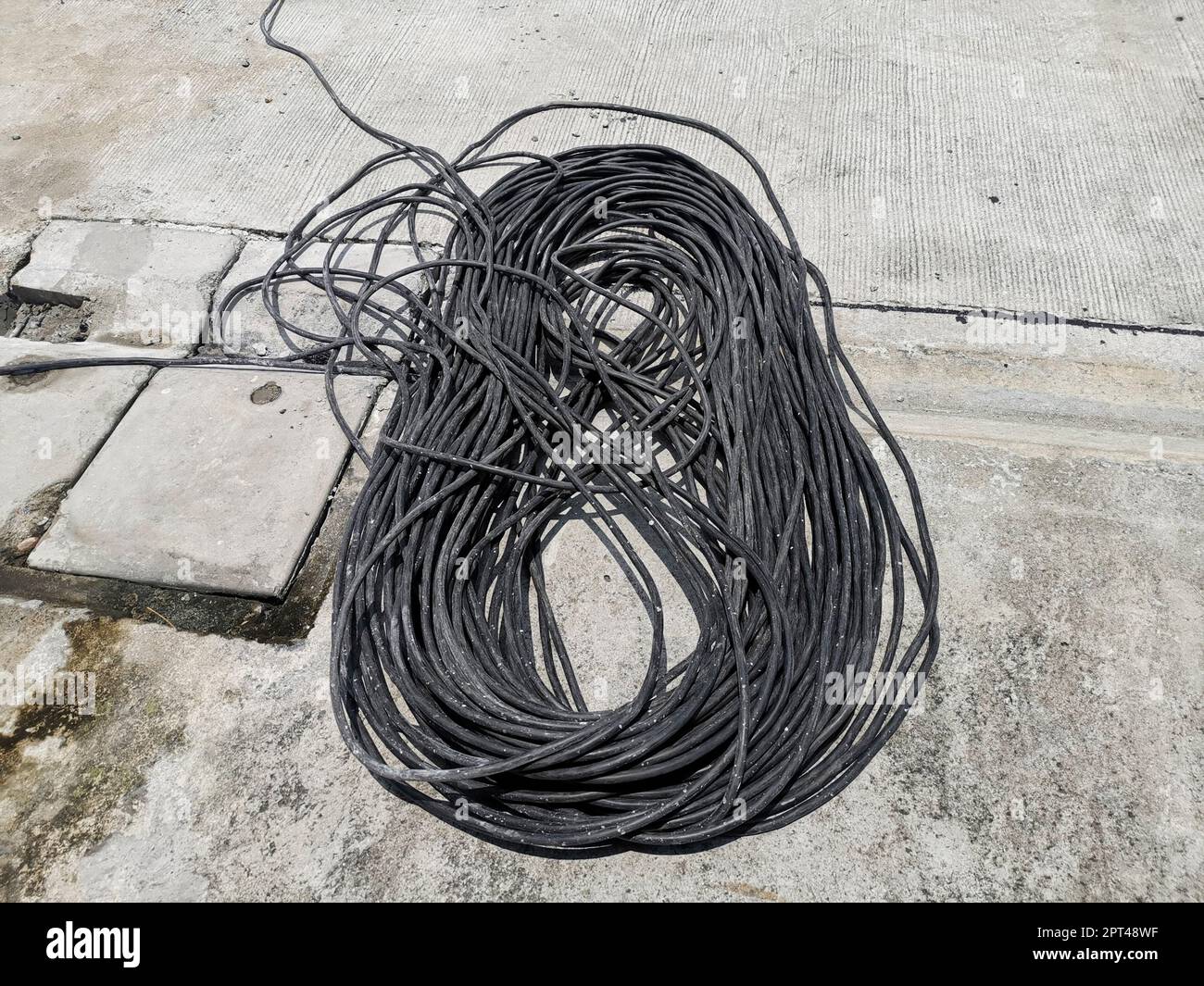 Black rolled electric cable on a road surface background Stock Photo