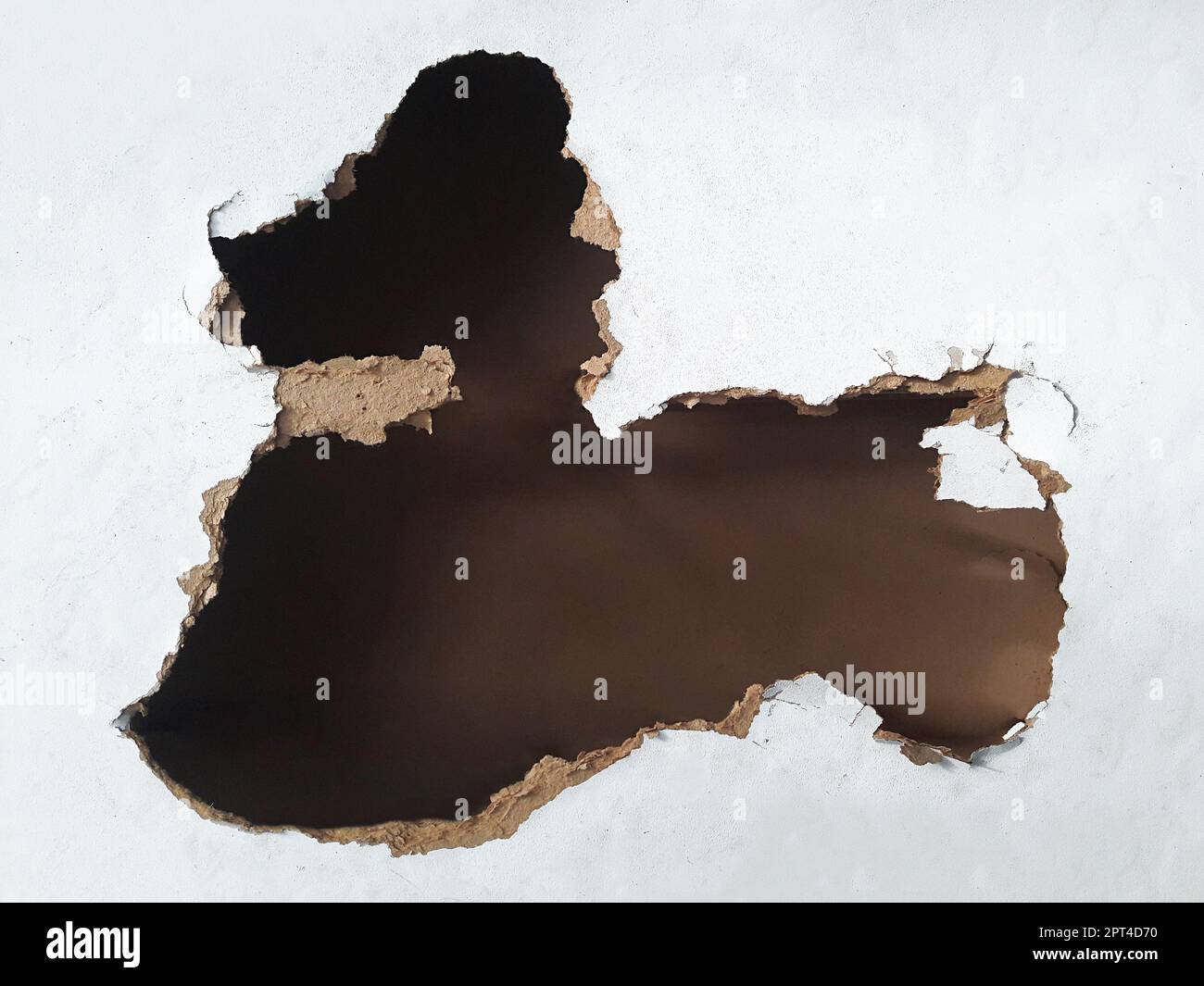 Hole in the fibreboard on black background Stock Photo - Alamy