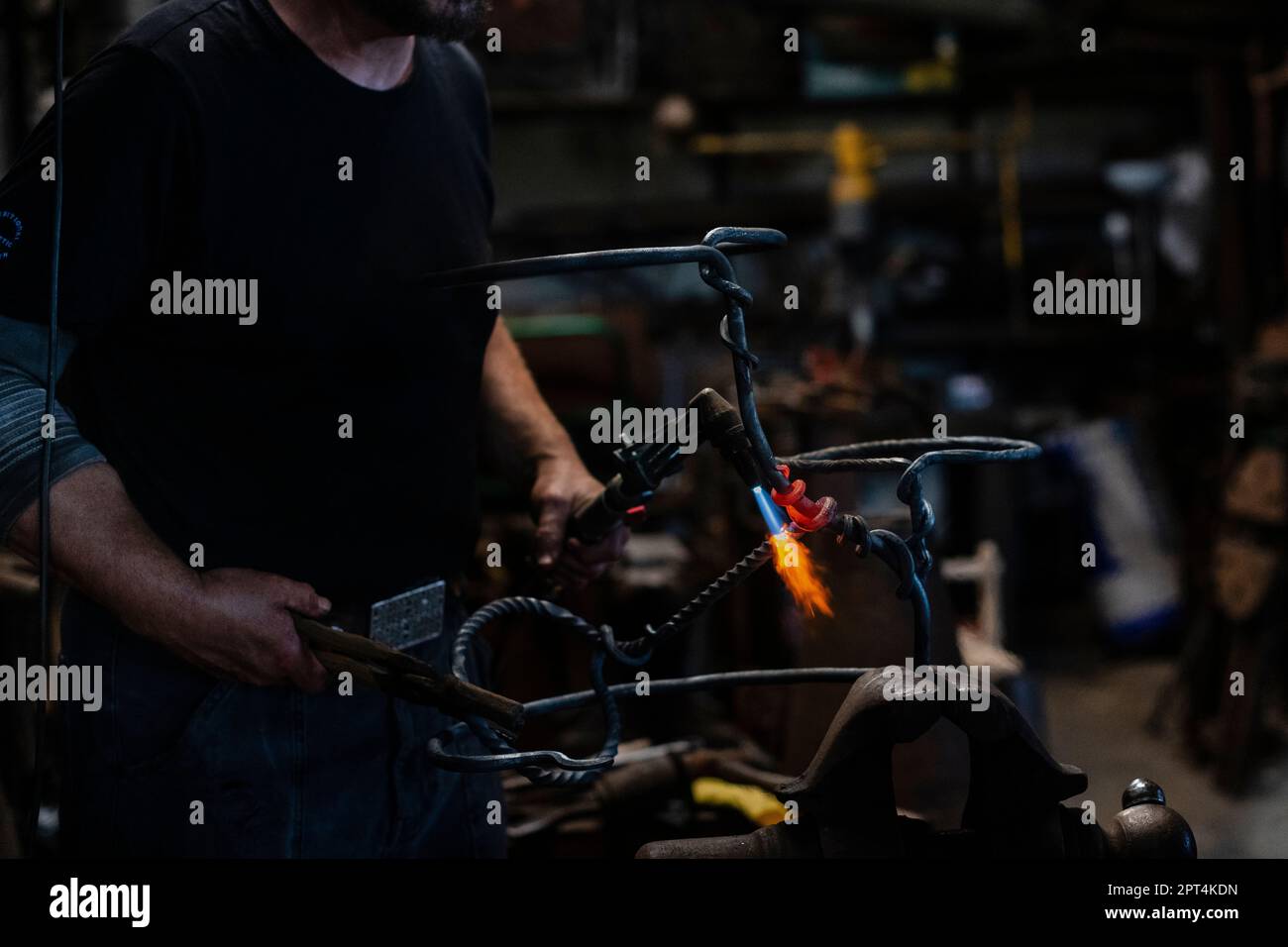 Blacksmith working in workshop on the vice with hot metals with anvile and flame forger Stock Photo