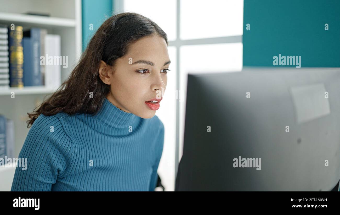 Young beautiful hispanic woman student using computer at university ...