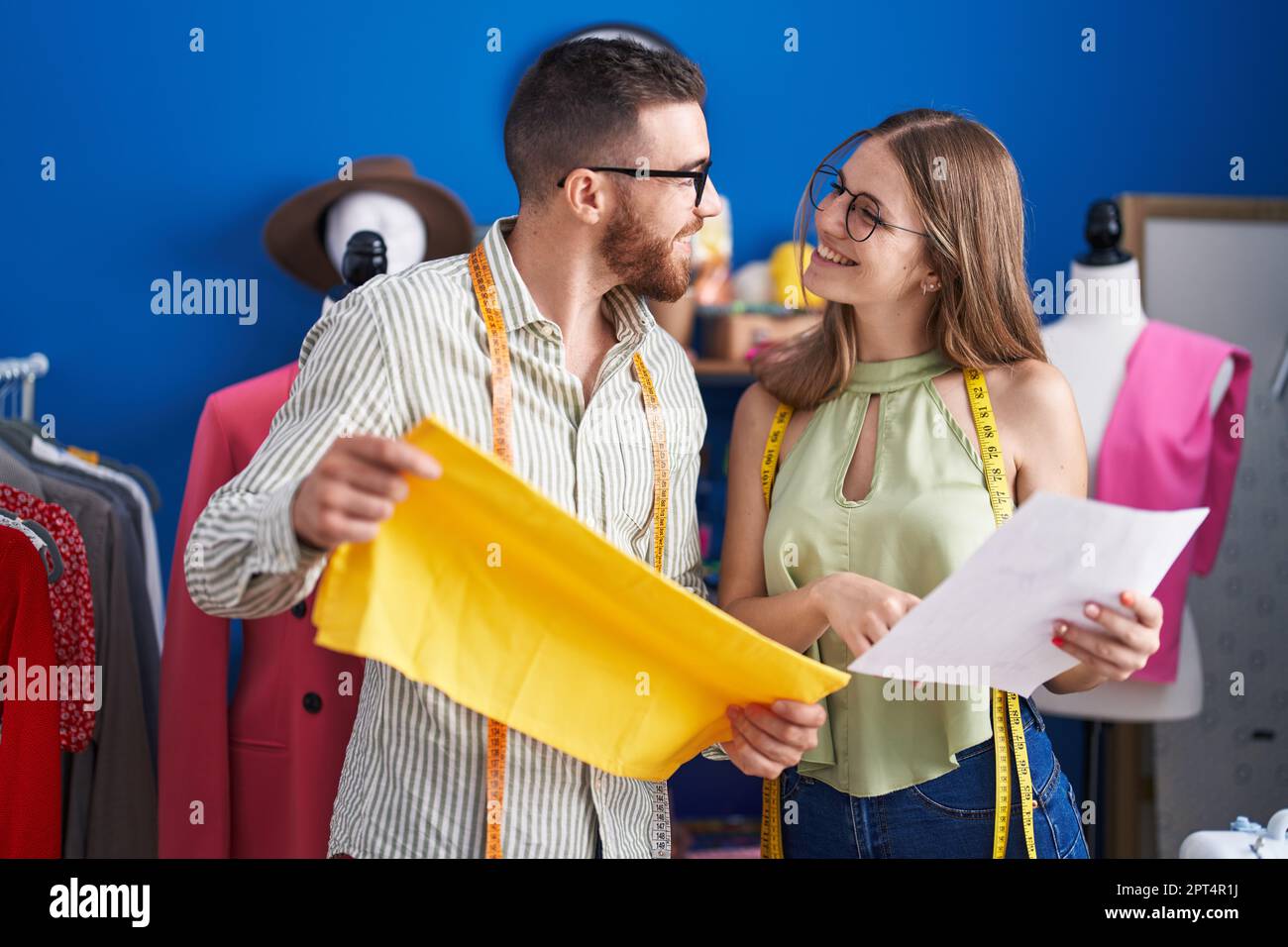 Man and woman tailors holding cloth looking clothing design at clothing ...