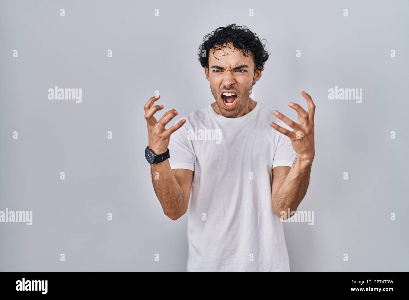 Hispanic man standing over isolated background crazy and mad shouting ...