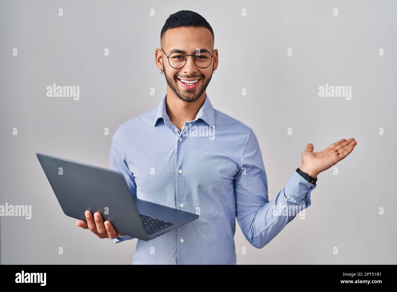 Young hispanic man working using computer laptop pointing aside with ...