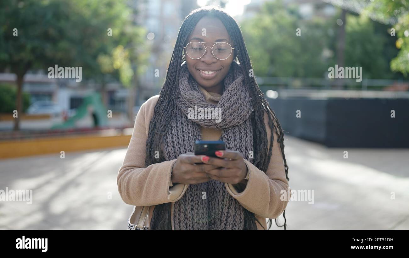 African woman smiling using smartphone at park Stock Photo - Alamy