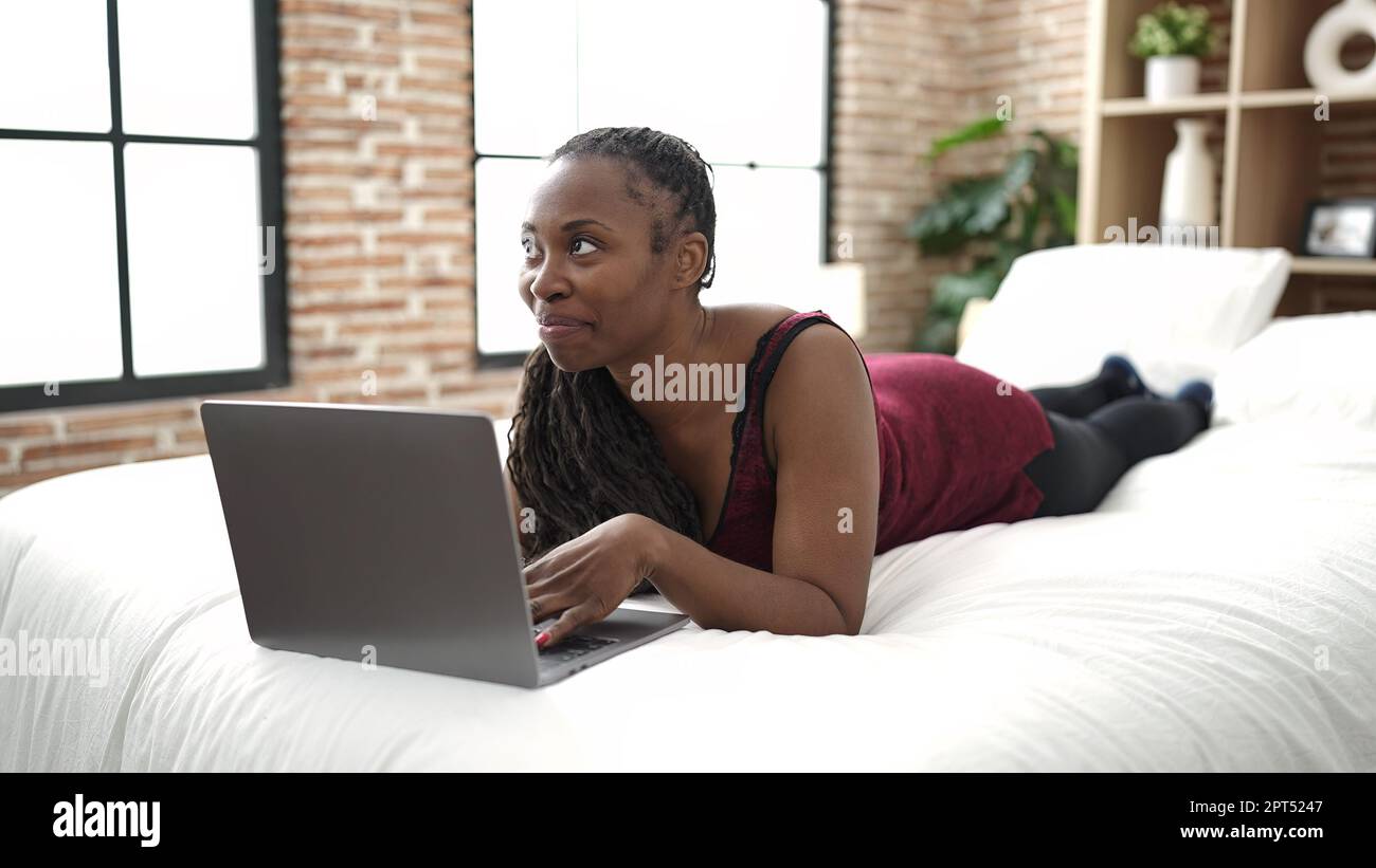 African woman using laptop lying on bed at bedroom Stock Photo - Alamy