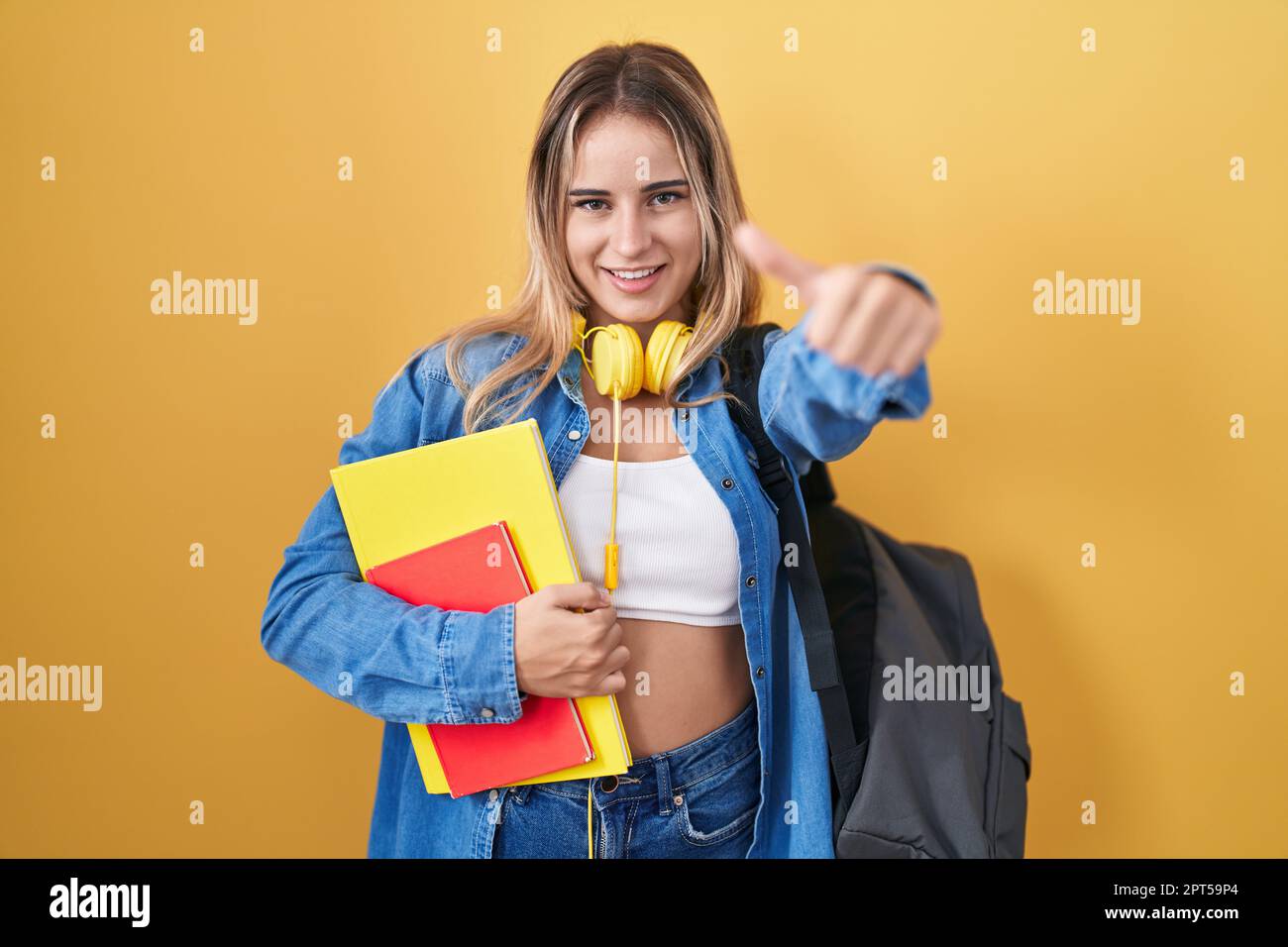 Young blonde woman wearing student backpack and holding books approving ...