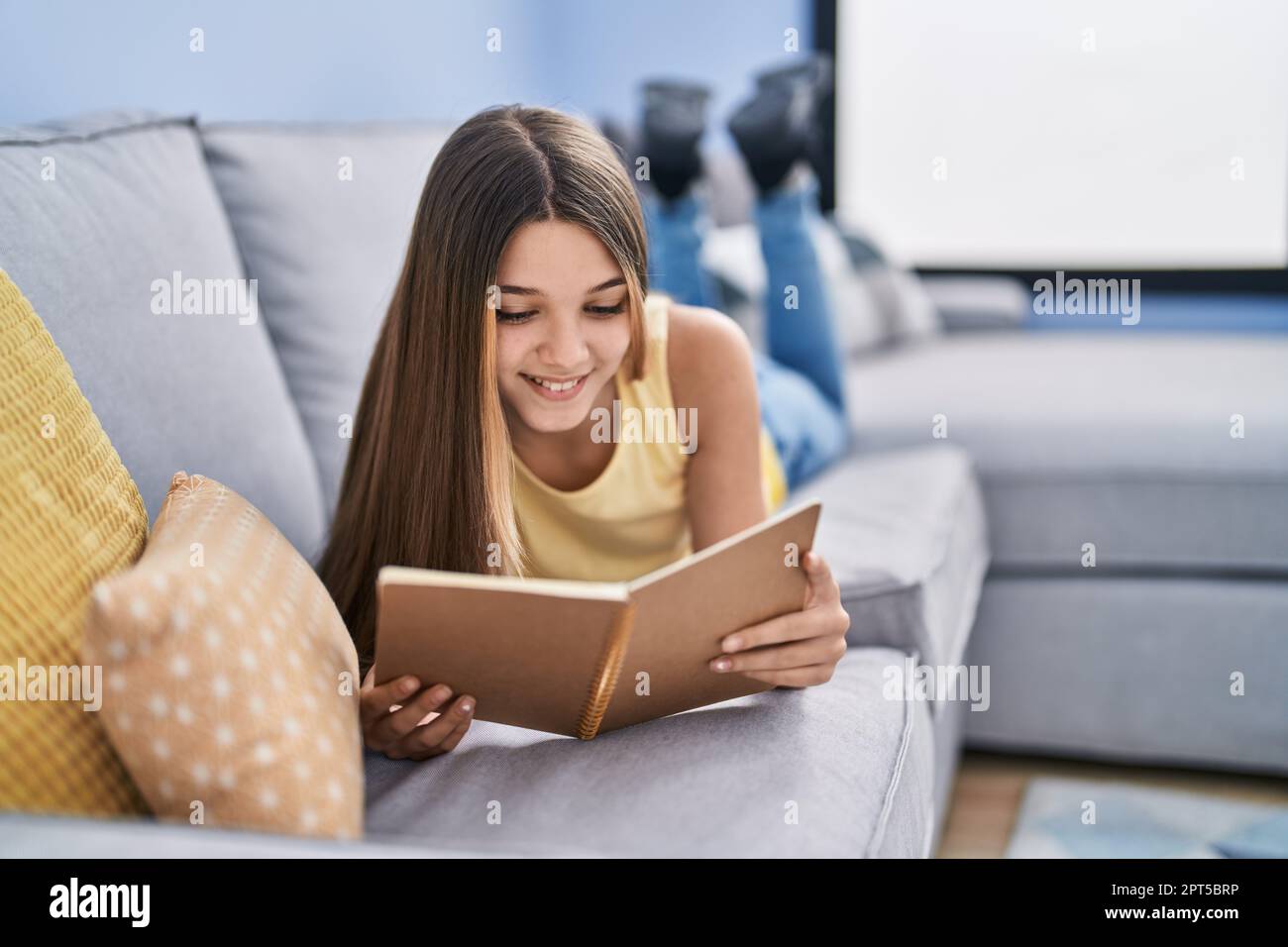 Adorable girl reading book lying on sofa at home Stock Photo - Alamy