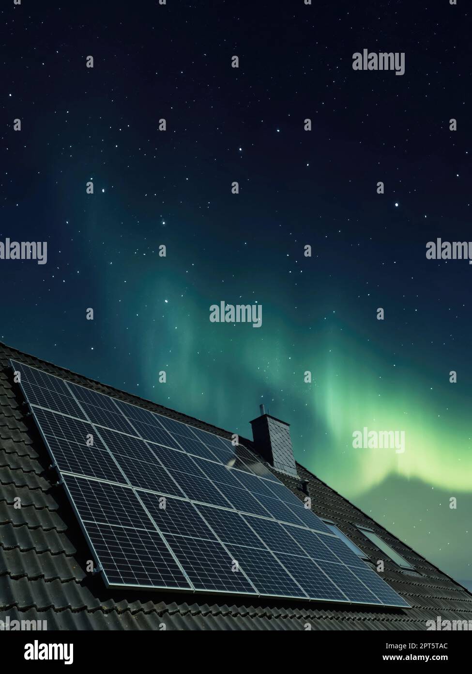 Solar panels producing clean energy on a roof of a residential house with aurora borealis in the background Stock Photo