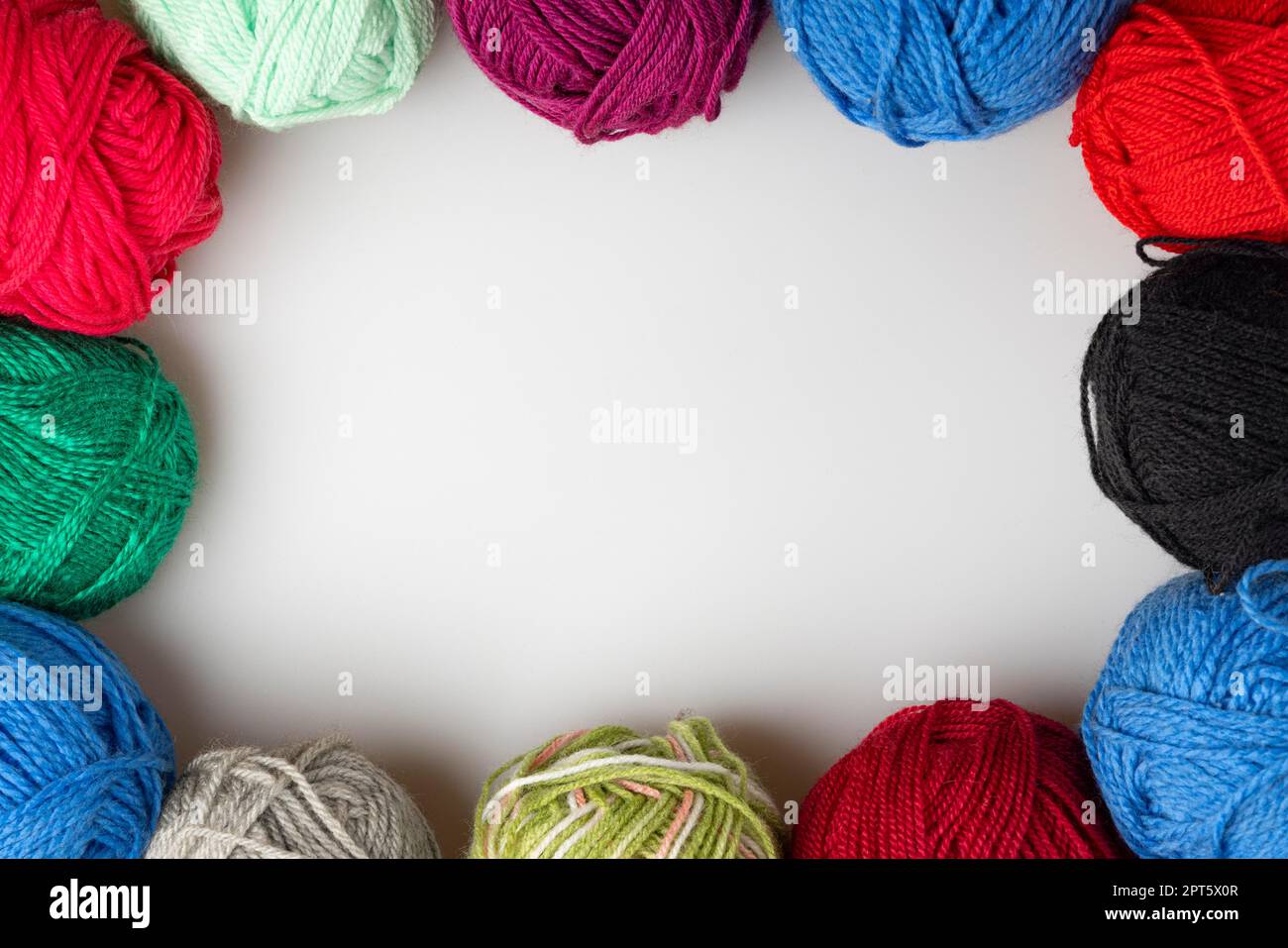 Different coloured balls of wool, frame, copying space in the middle, white background Stock