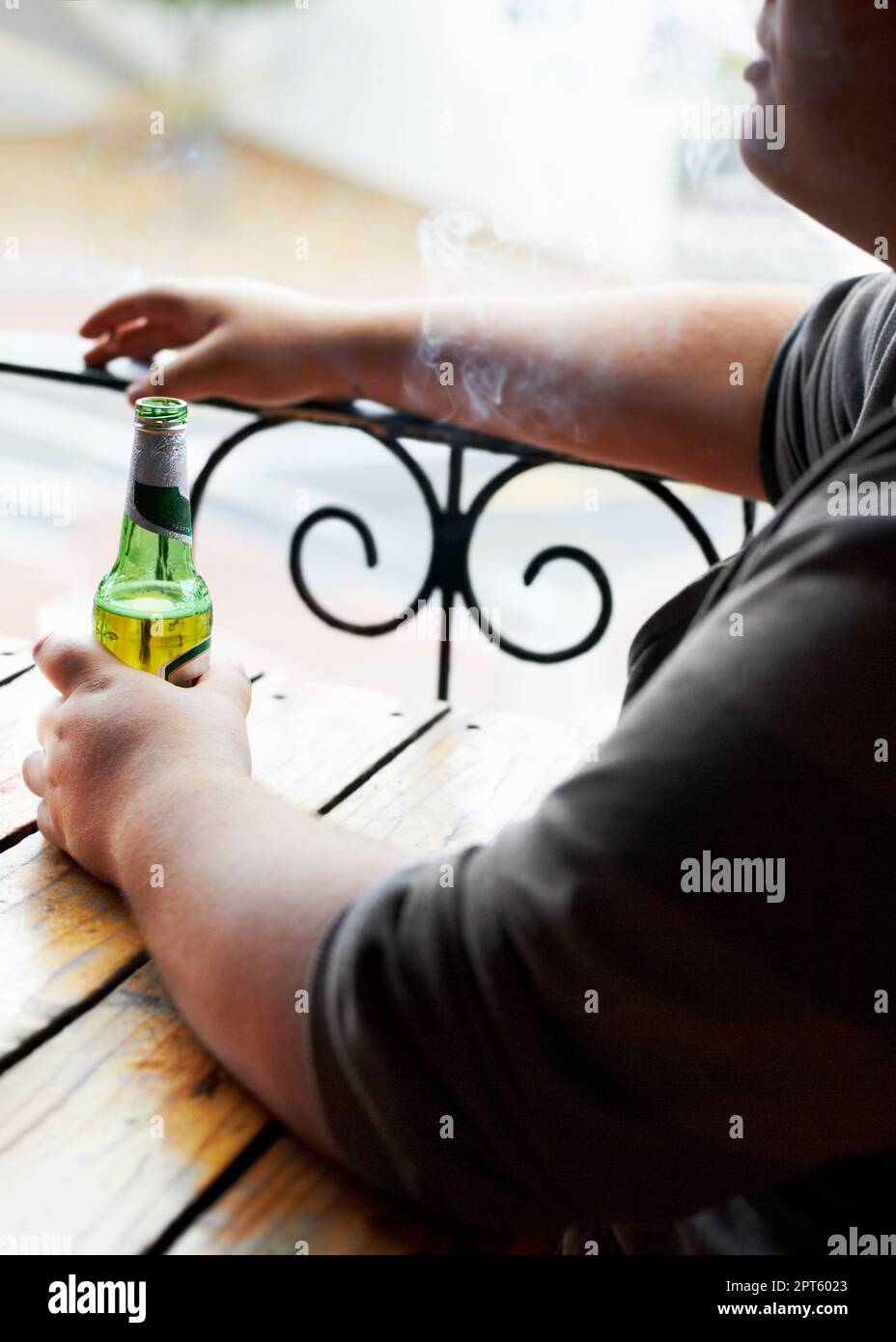 Indulging in lifes little pleasures. A cropped image of a young man smoking while sitting with a beer in front of him Stock Photo