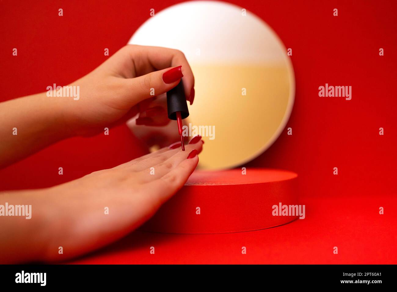 Young caucasian girl put her hands on a red podium and paints her nails