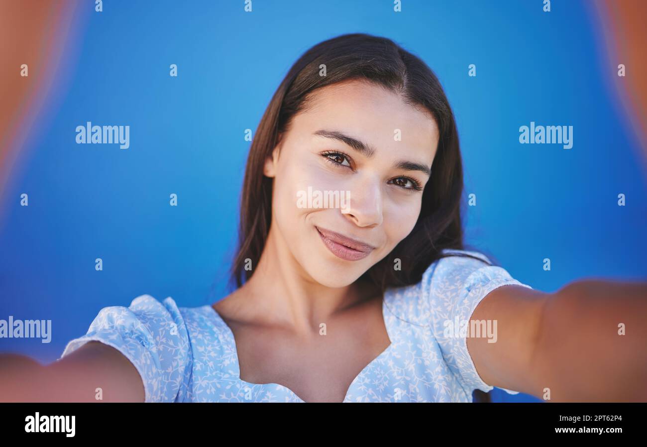 Smile, happy and taking selfie with woman showing face during travel  against blue background. Pov portrait of smiling female with natural beauty  takin Stock Photo - Alamy