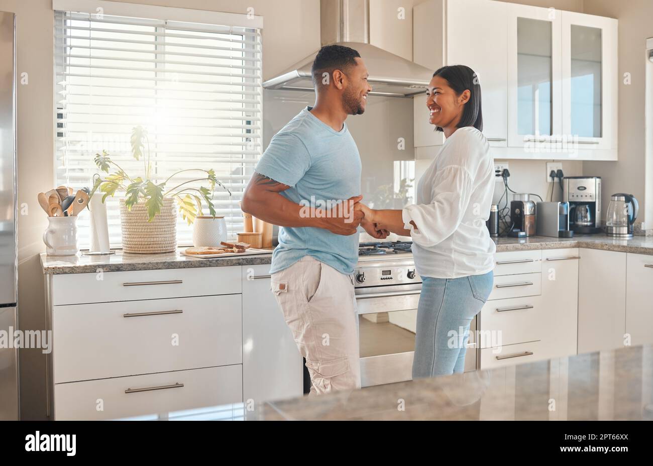 Beautiful sexy girl in underwear and earphones listening to music using a  smartphone, dancing and smiling while cooking in the kitchen. Young woman  with perfect body posing in kitchen in the morning