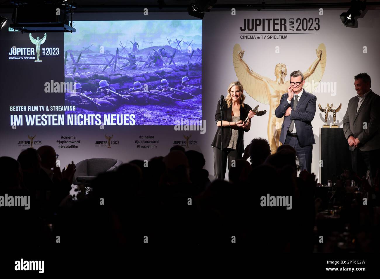 Hamburg, Germany. 27th Apr, 2023. Sasha Bühler (l-r), Netflix, Malte Grunert, film producer, and Gerd Nefzer, German special effects artist and laudator of the award, are on stage at the Jupiter Award 2023 ceremony. The Netflix production 'Nothing New in the West' was honored as Best Film TV & Streaming (National). For the 45th time, the magazines 'TV Spielfilm' and 'Cinema' presented the audience award for outstanding film productions and stellar acting performances. Credit: Christian Charisius/dpa/Alamy Live News Stock Photo