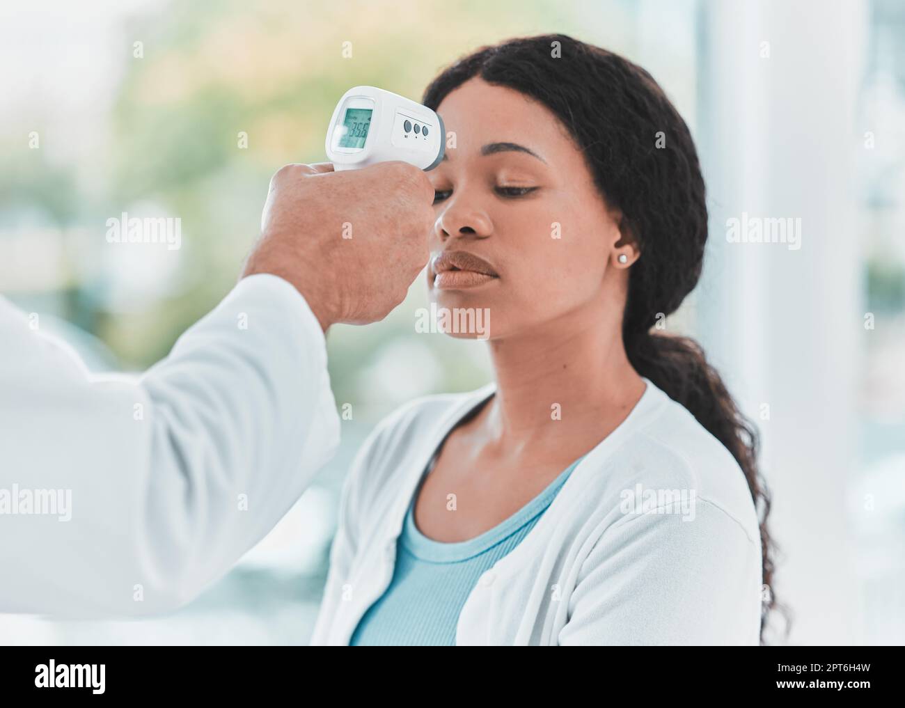 Have you been feeling warm lately. a doctor scanning a patients temperature using a thermometer