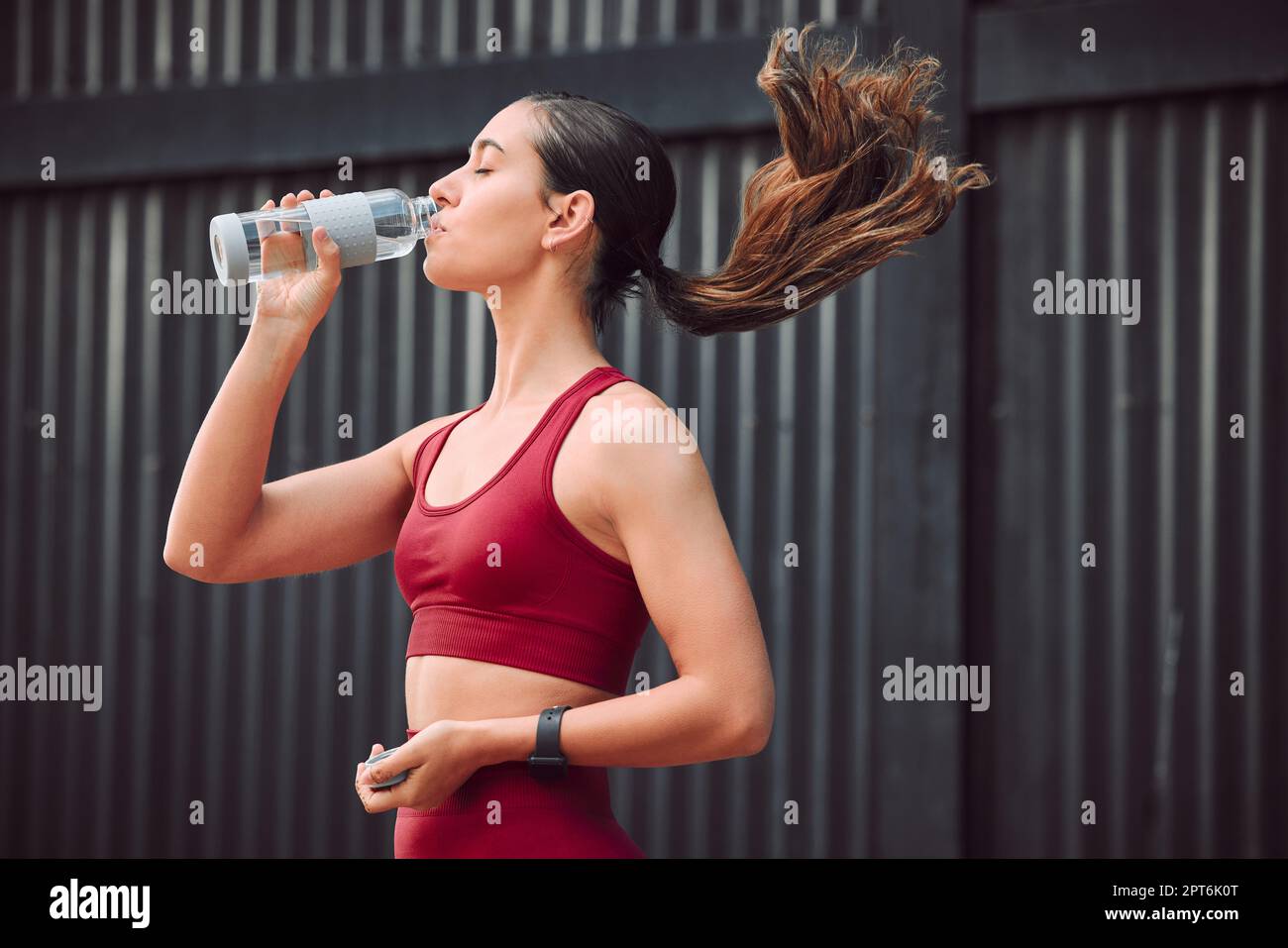 Topping up. an attractive young female athlete drinking water while running outdoors Stock Photo