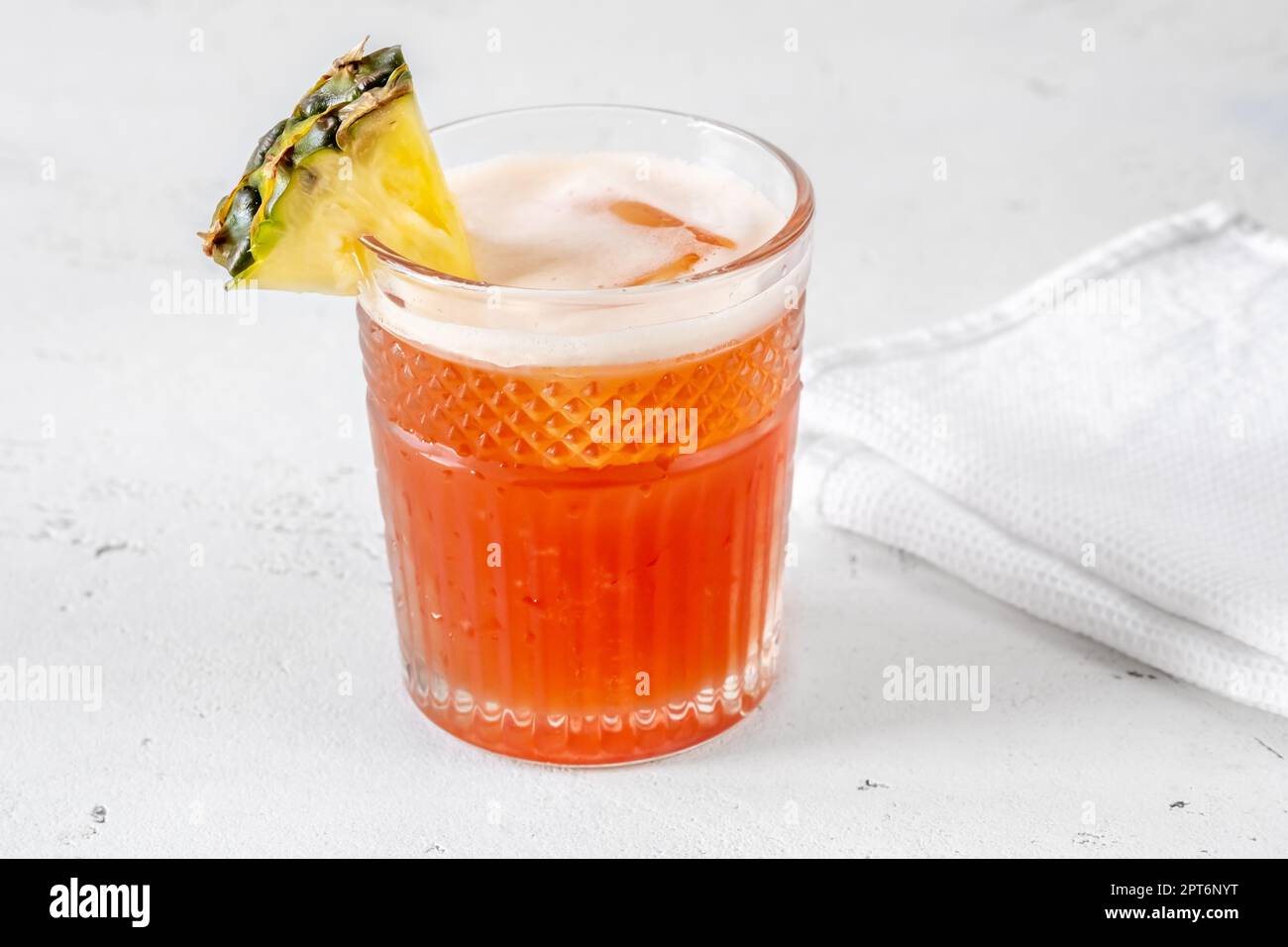 Glass of Jungle Bird cocktail garnished with pineapple wedge Stock Photo