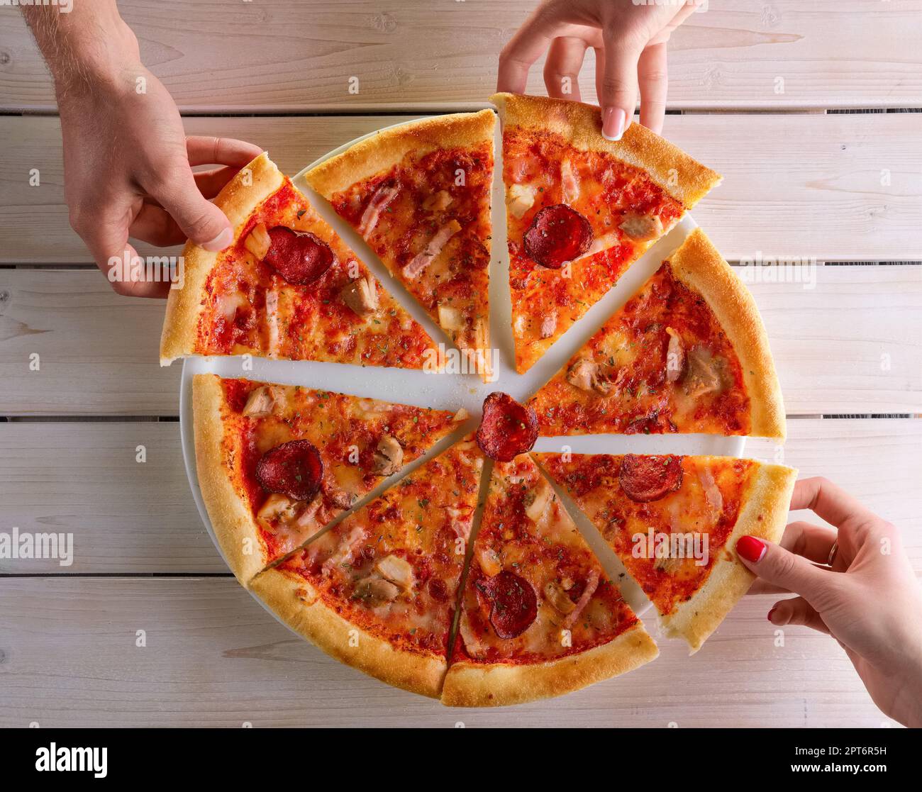 Close-up of people hands taking slices of pizza. Sharing food. Group of friends having pizza together. Stock Photo