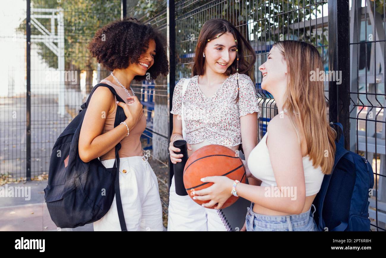 Multicultural group of young female friends bonding outdoors and having fun. Stylish cool teen girls gathering at basketball court, friends ready for Stock Photo