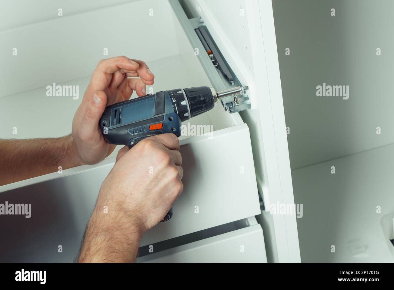 Male hands hold cordless electric screwdriver, screw to fix rail ...