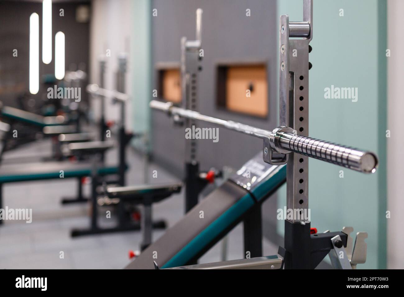 Vertical weight lifting equipment. Close up of empty barbell bar without plates on rack in gym club. High quality equipment and gym maintenance. Selec Stock Photo
