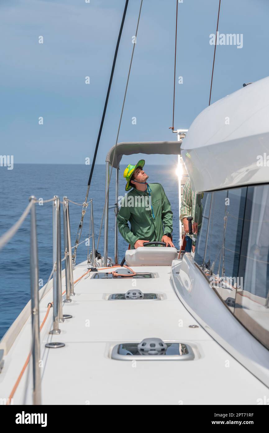 Skipper at the wheel, young man sailing a sailing catamaran, Rhodes
