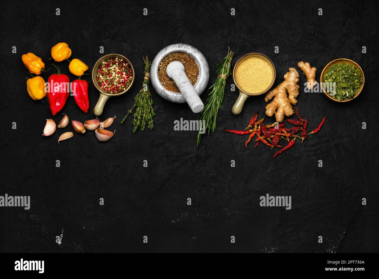 Composition with mixture of peppers, ginger, garlic, thyme, chilli and rosemary on dark background Stock Photo