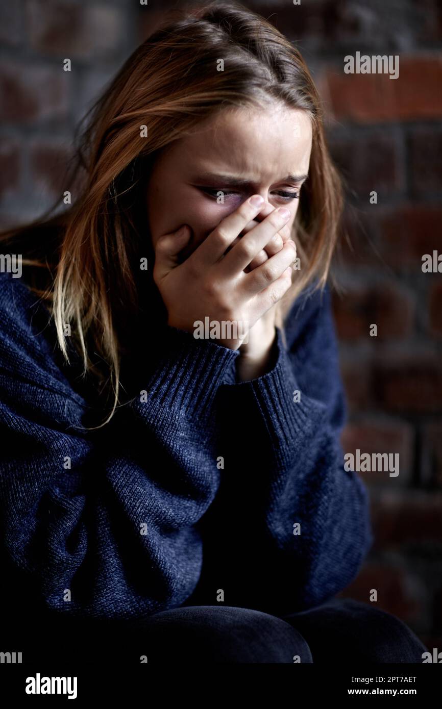 Broken down emotionally. Abused young woman crying hard and covering