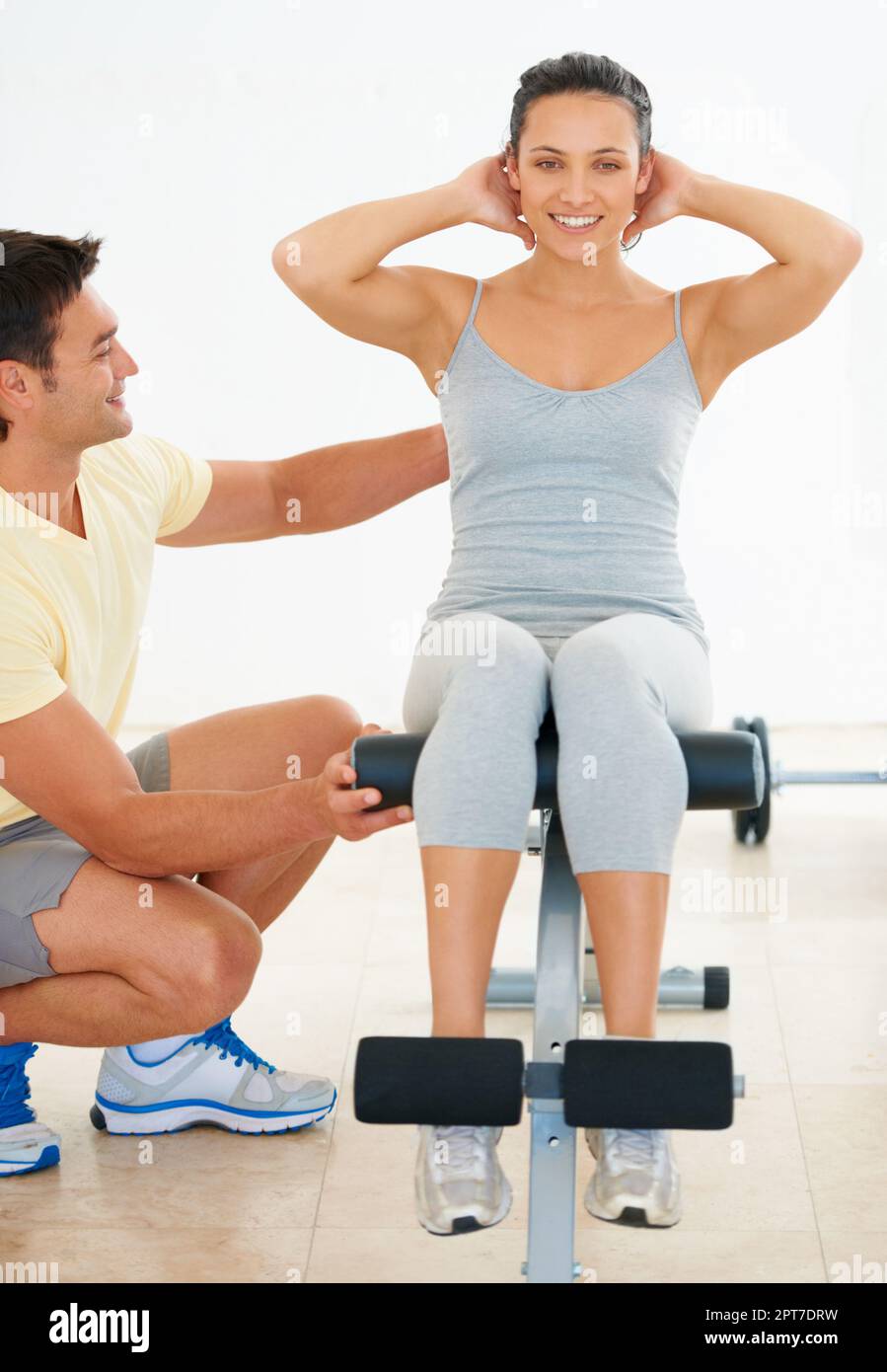 Helping her exercise correctly. A fitness instructor showing a young woman how to do an exercise