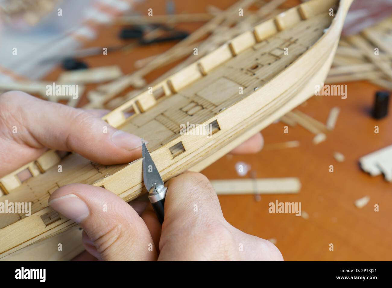 Hands of man cutting out details for ship model with clerical knife ...