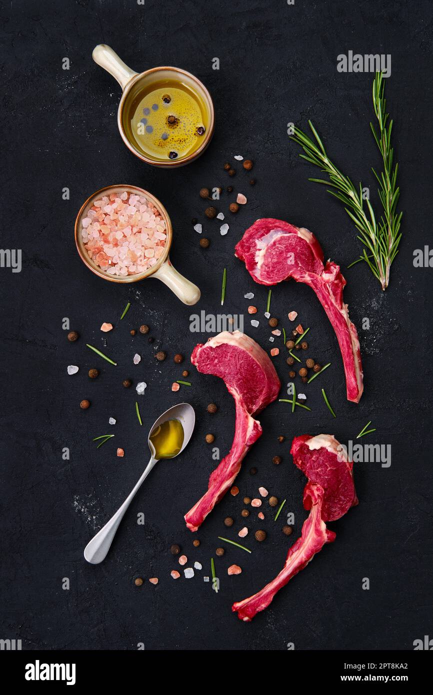 Composition with rack of lamb, seasoning and herbs on dark background