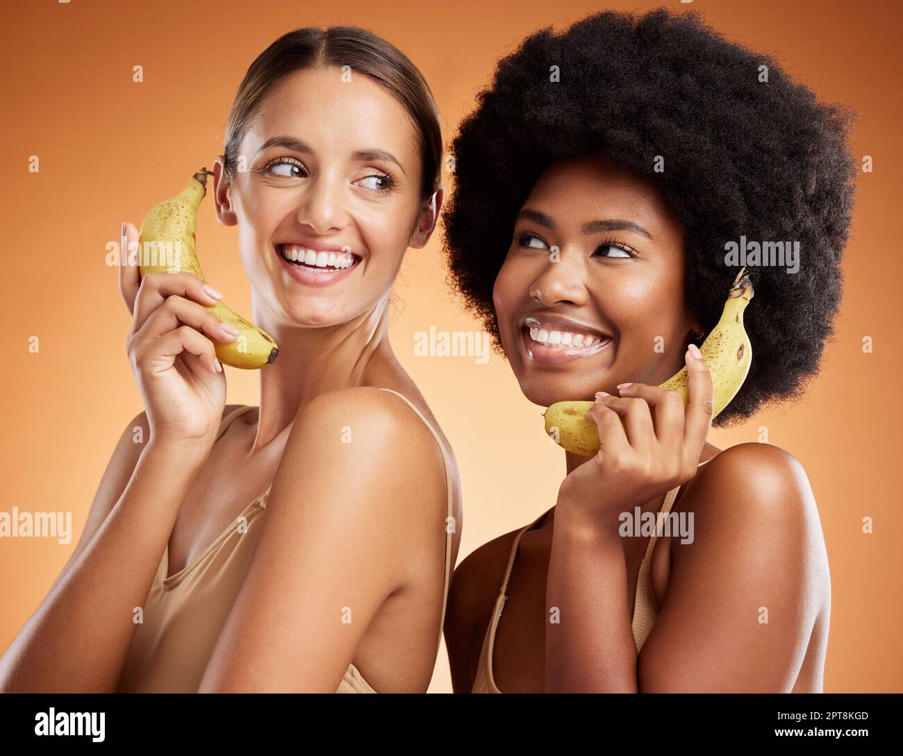 Beauty, diversity and women on banana phone, black woman and friend act, smile and fun pretending to be on phone call. Playful, friendship and studio Stock Photo