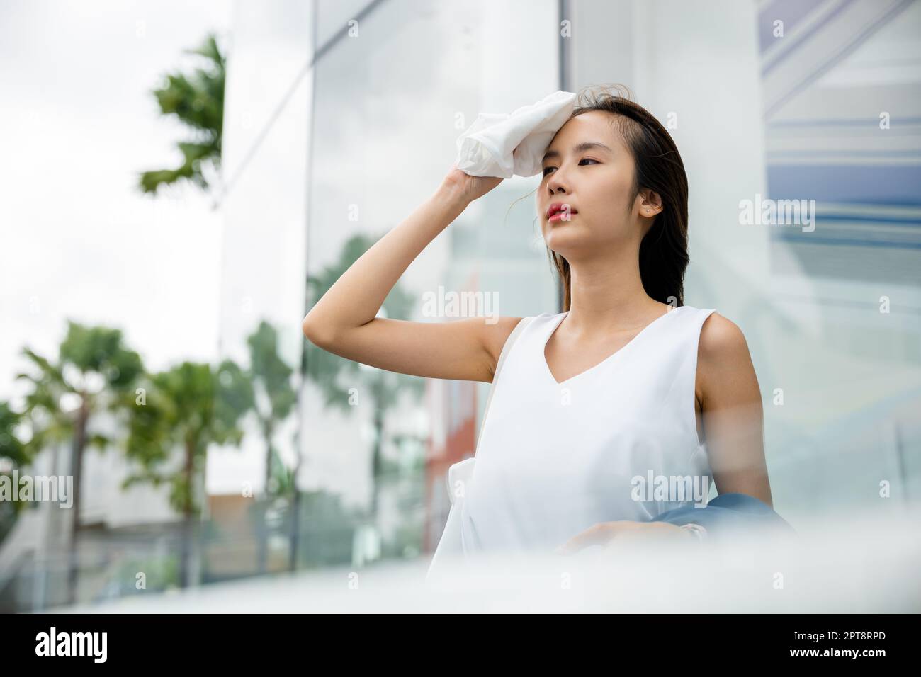 Asian beautiful business woman drying sweat her face with cloth in warm summer day hot weather, Female having sunstroke skin damage from sun UV city a Stock Photo