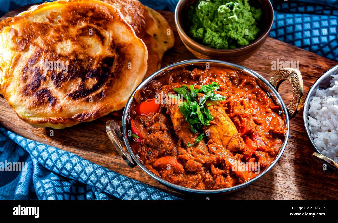 Butter chicken with rice and naan flatbread served in original indian karahi pots Stock Photo