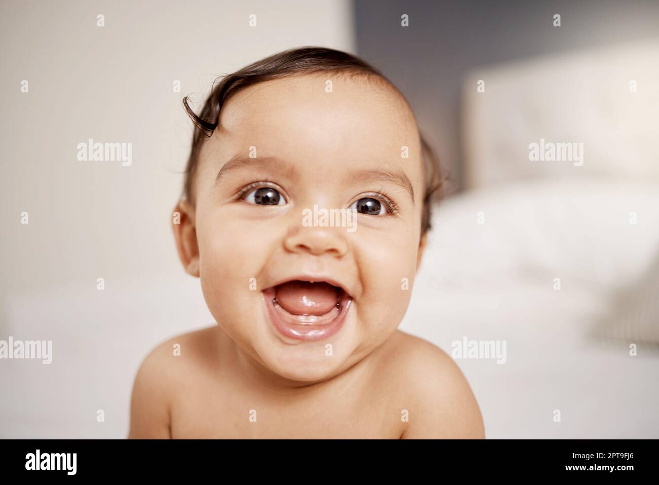 Shes one happy baby. an adorable baby girl sitting on a bed Stock Photo