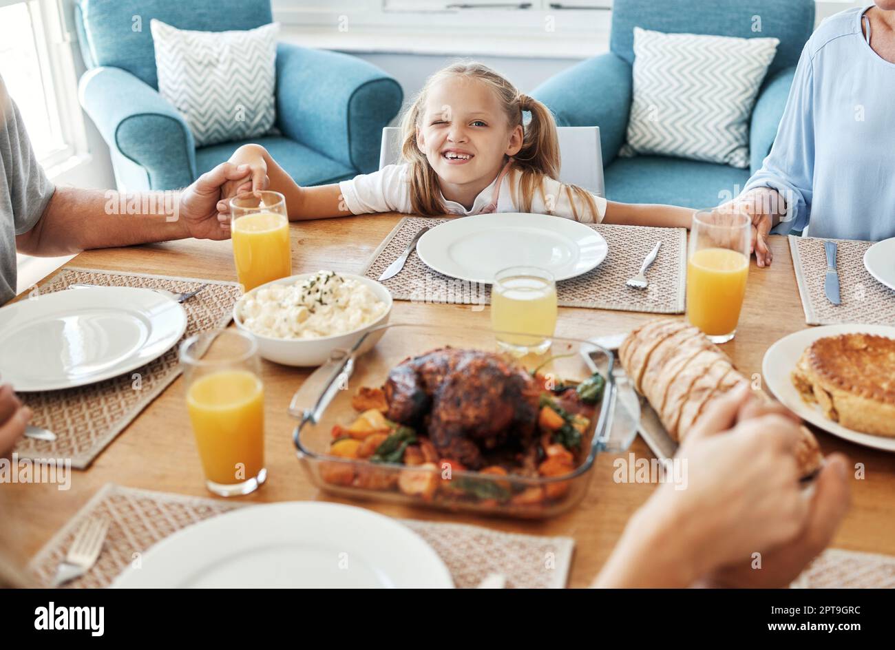 Food, family and praying with girl at a table, holding hands in