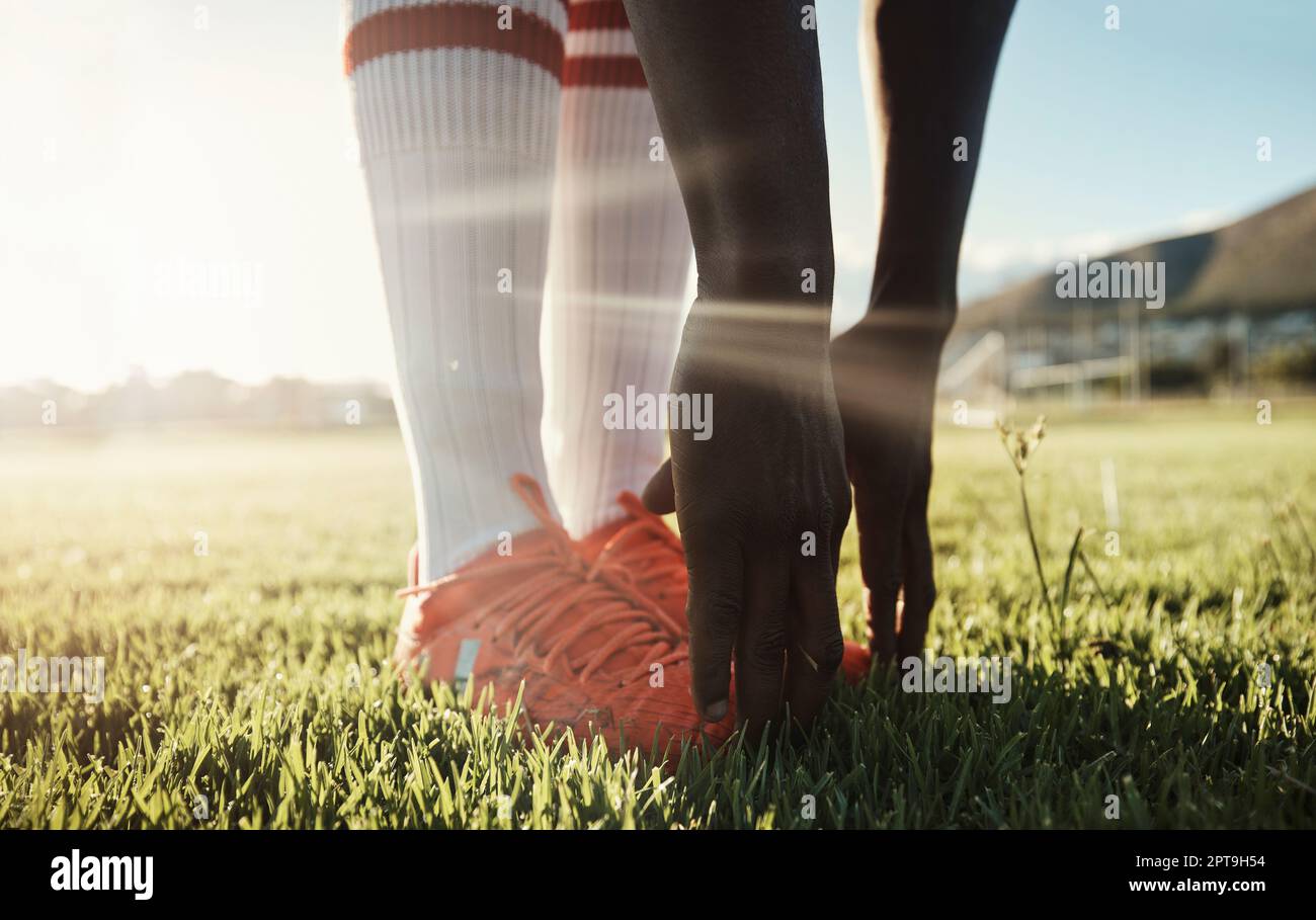 Soccer player, stretching legs on grass and hands on shoes on pitch for