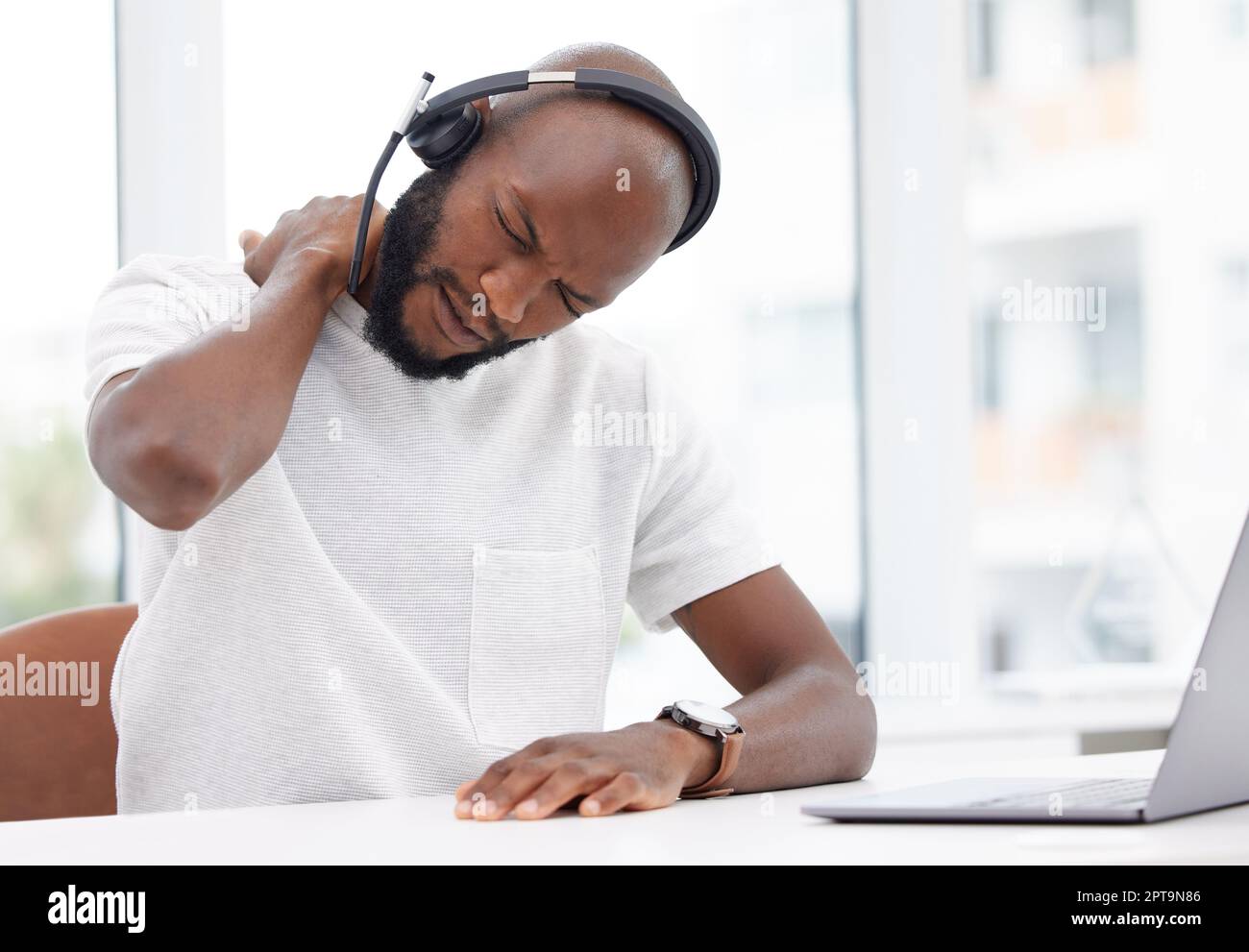 This neck cramp is no joke. a young male call center worker experiencing neck pain at work Stock Photo