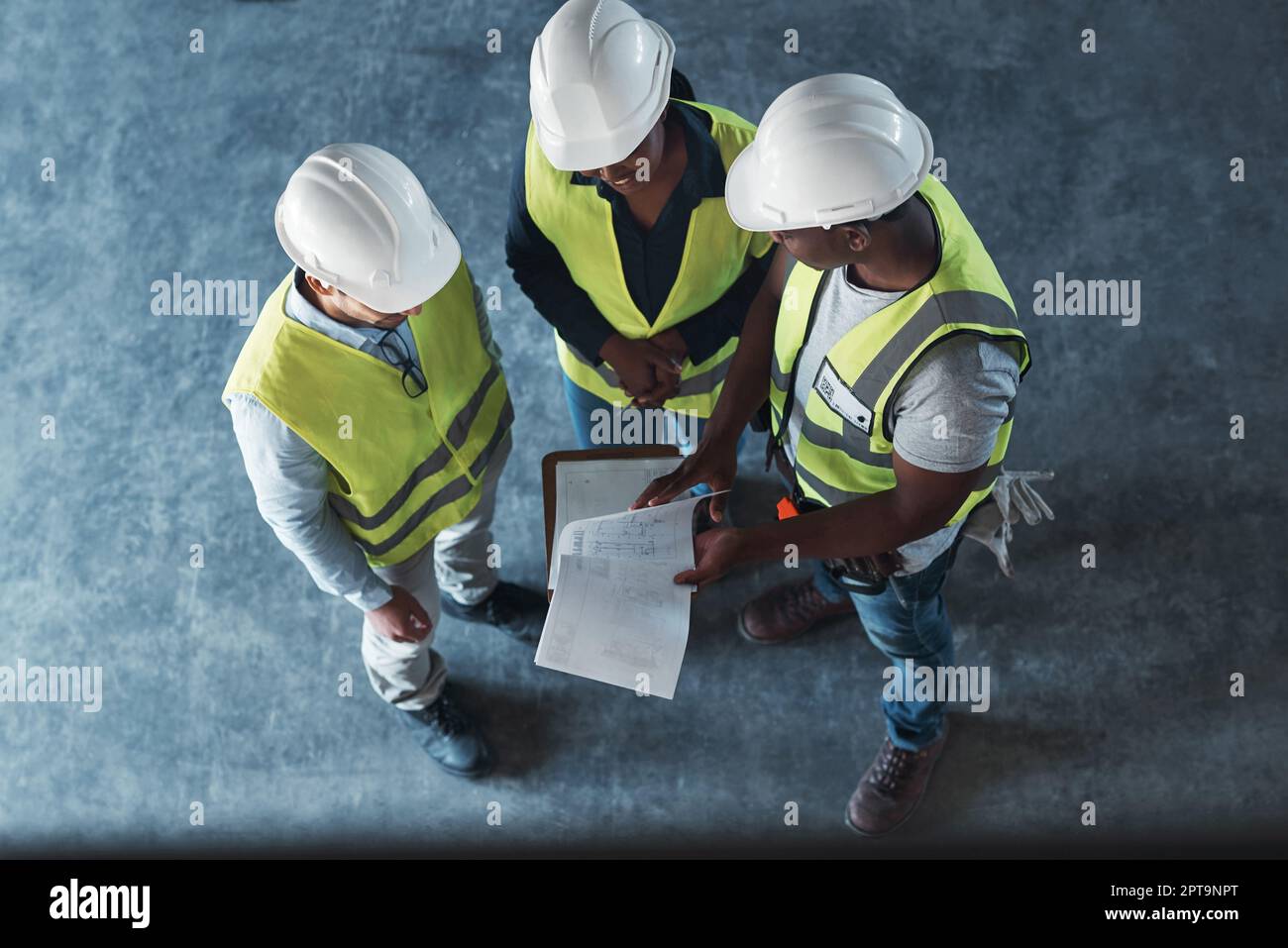 Everything seems to be in order on paper. High angle shot of a group of contractors standing in the warehouse together and having a discussion Stock Photo