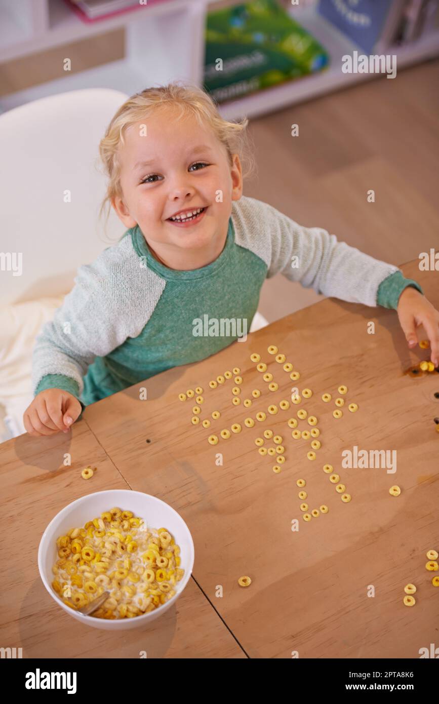 Shes a whiz kid. High angle shot of a cute little girl doing equations using her breakfast at home Stock Photo