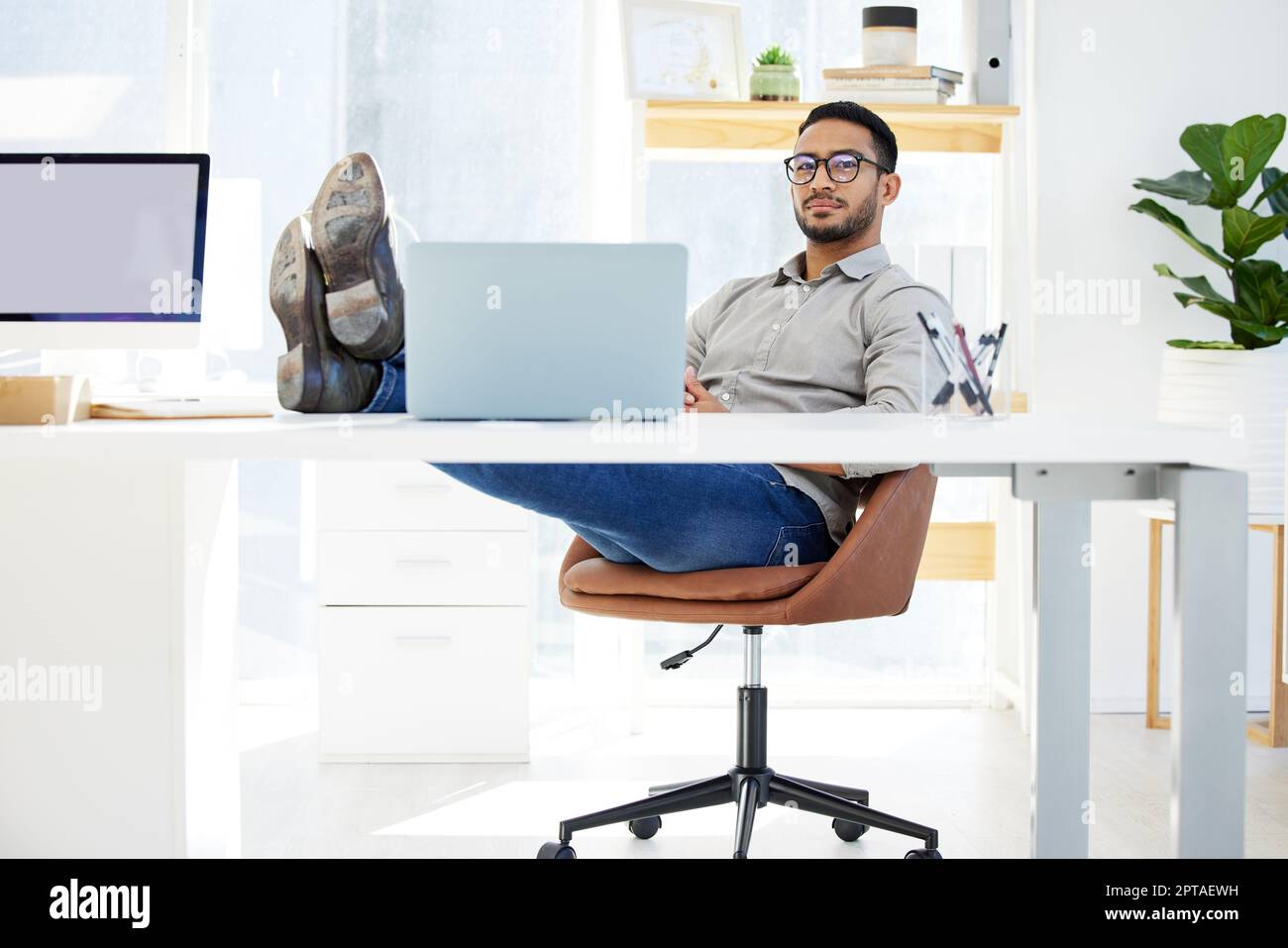 Time to kick the feet up. a young man putting his feet on the desk at