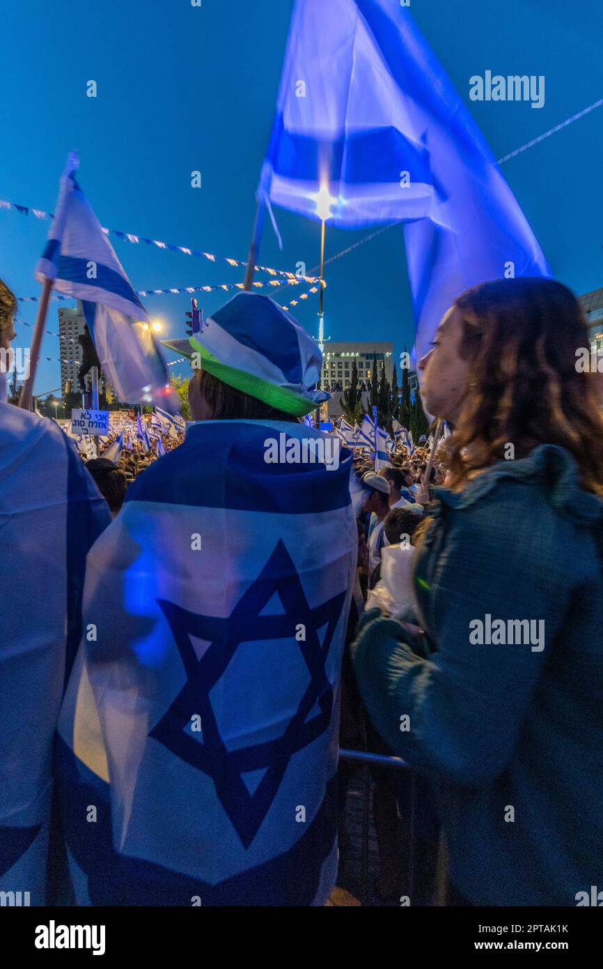 Israel. A woman covered with a Israeli flag, with a flag-themed hat, and holding a Israeli flag, stands during a rally to support Judicial reforms. One of the largest demonstrations in the history of the country was held in support of the proposed Judicial reforms, which became hotly debated between those who see them as neccessary to fix the excessive powers of the court, and those who see those reforms as a danger to Israeli democracy. Stock Photo