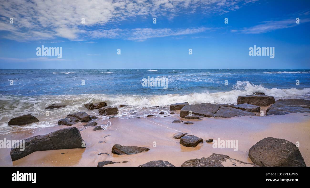 Rocky beach at Alexandra Headland, Maroochydore, Sunshine Coast, Queensland. The tide is coming in, sand is wet and surf waves breaking over the rocks Stock Photo