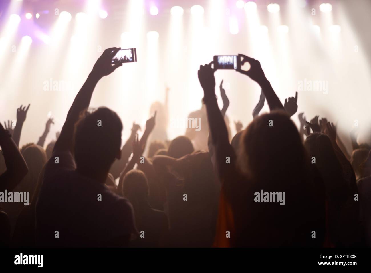 Catching the band in action. Rearview shot of fans filming a band on ...