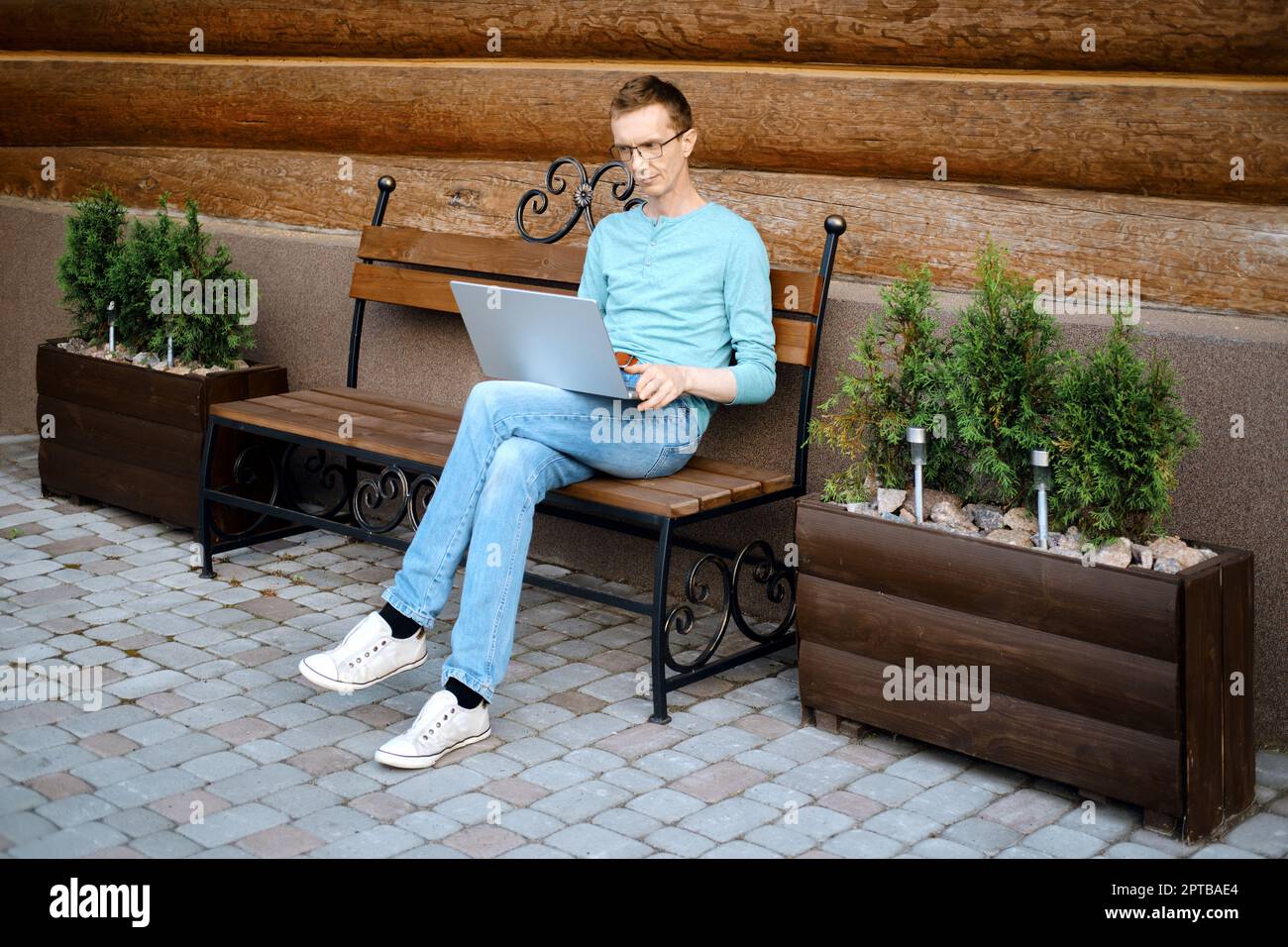 Middle aged man makes online order using laptop outdoors Stock Photo