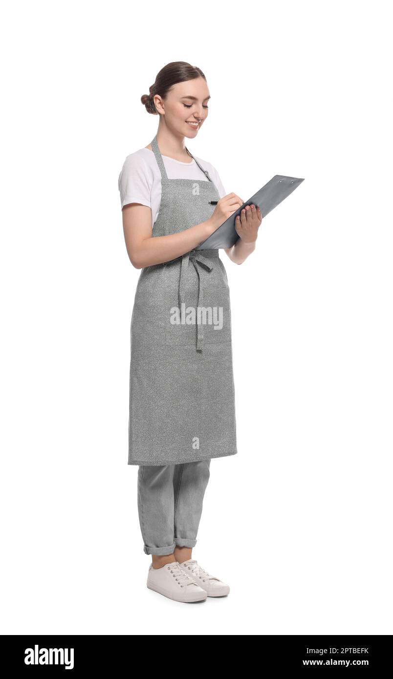Beautiful young woman in clean apron with clipboard on white background ...