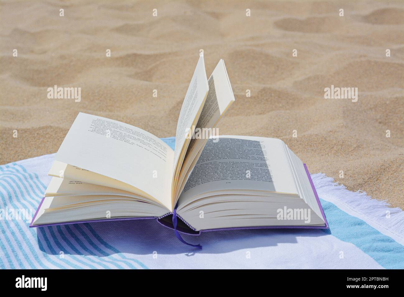 Beach towel with open book on sand Stock Photo - Alamy