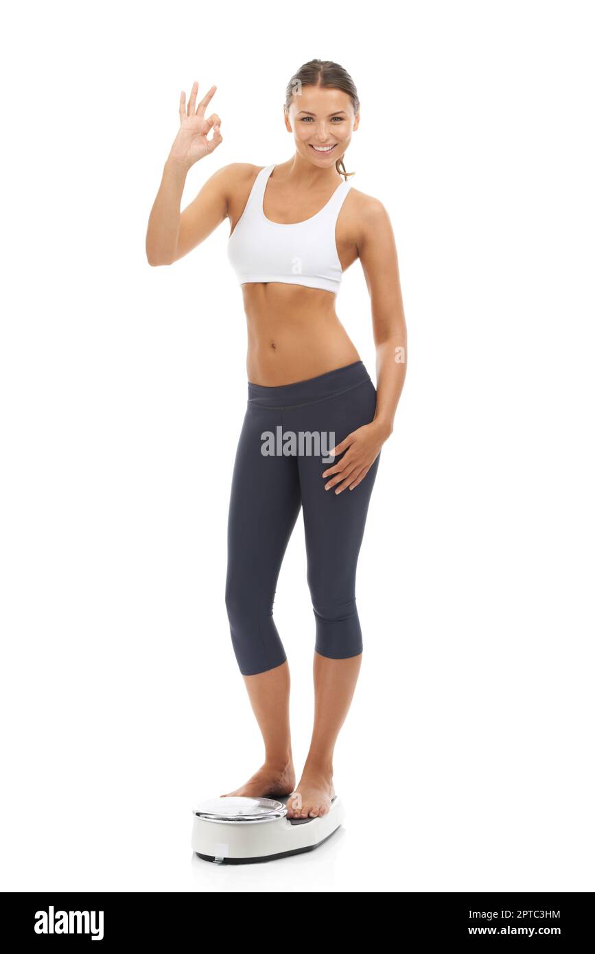 Happy woman smiling on weighing scales at gym. Trainer with female client  checking fitness progress. Personal training programme for weight loss  Stock Photo - Alamy