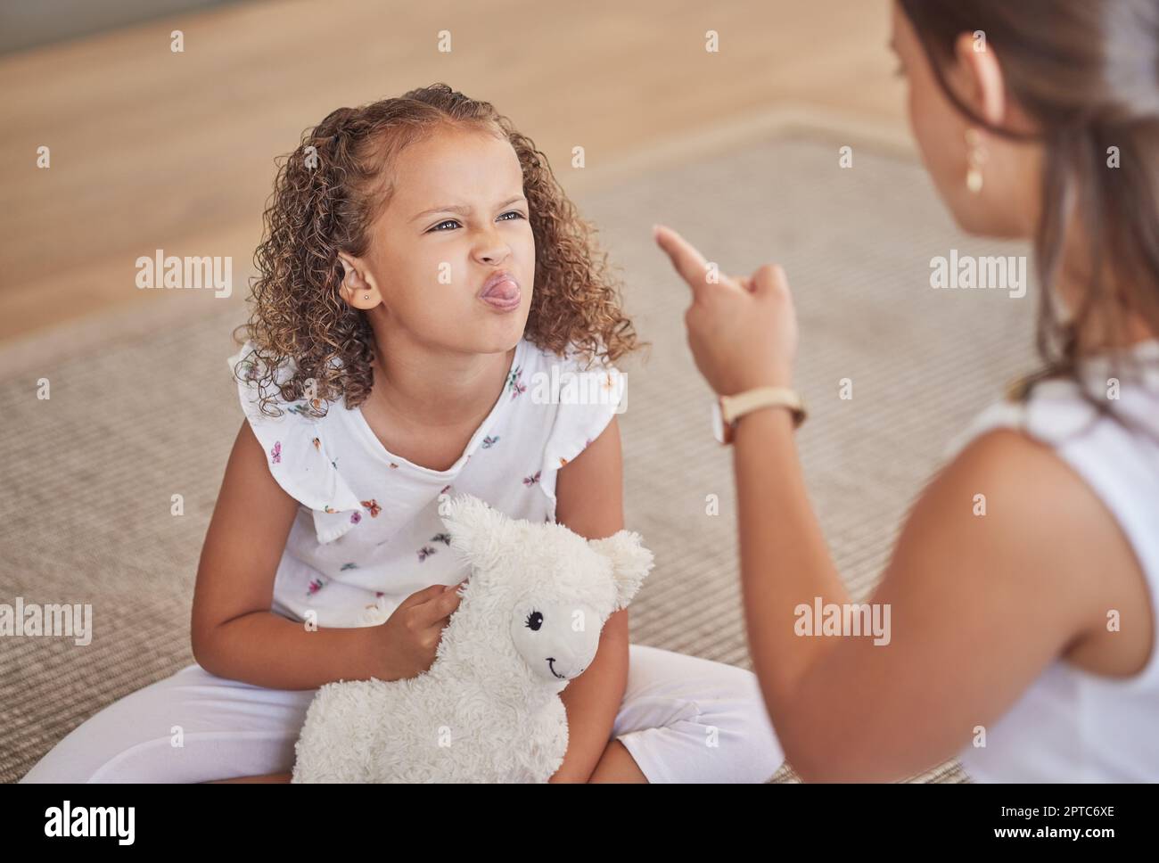 Angry, adhd and child being rude to her mother showing anger, bad behaviour and attitude problems at home. Mean, moody and girl with tongue out making Stock Photo